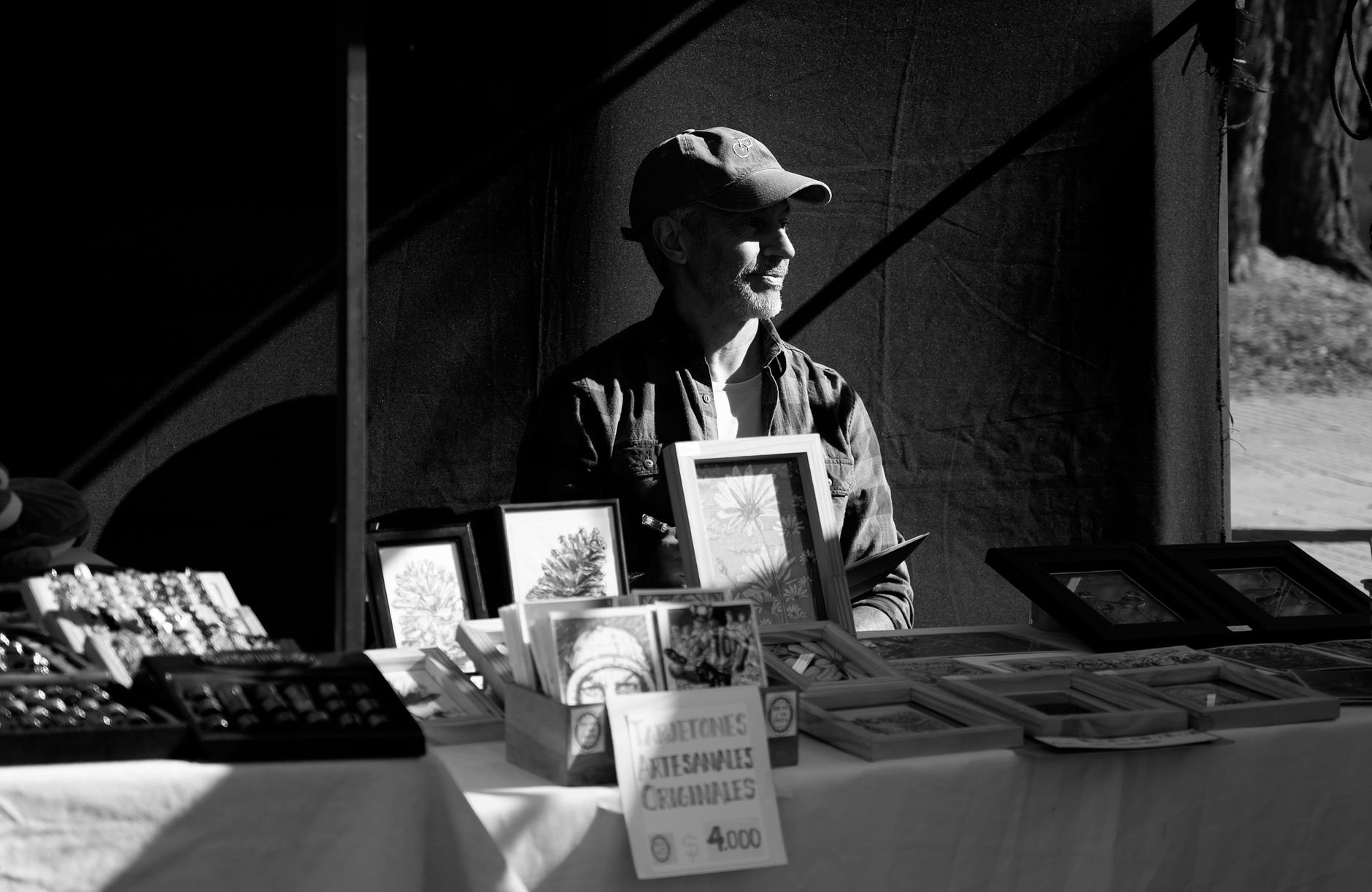 Black and white photo of an artisan vendor at a street market in La Plata, Argentina.